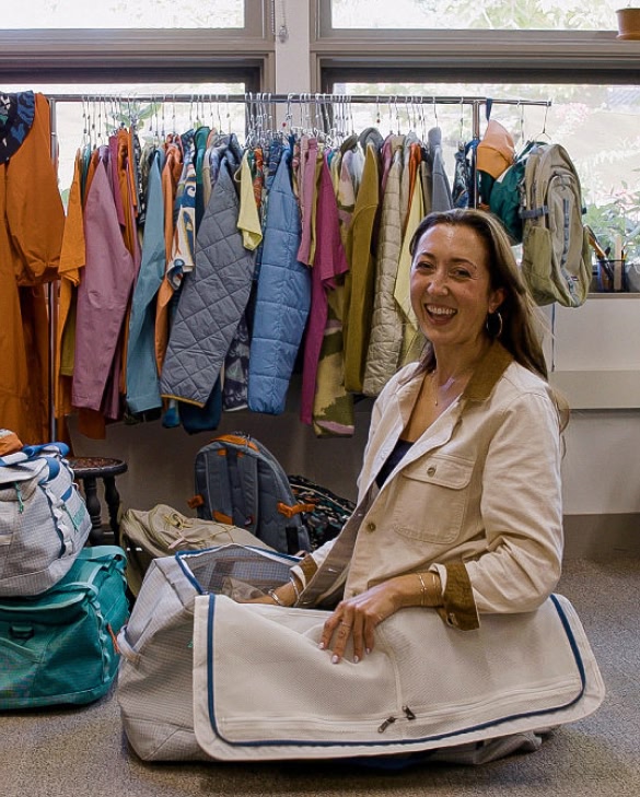 A person sits in a duffel bag and smiles.