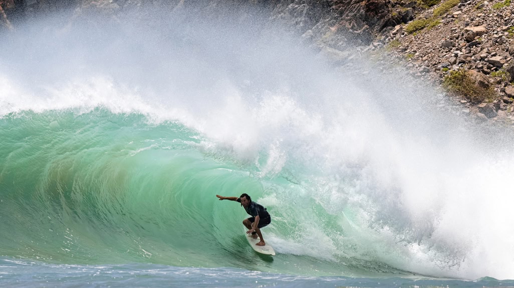 Surfer high-lining in the tube.