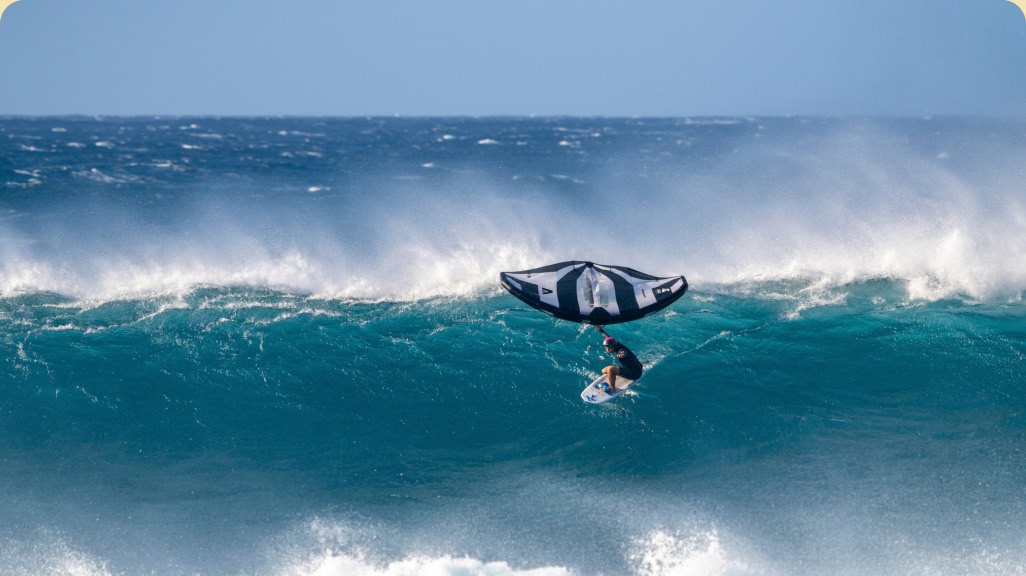 A surfer riding a wave on a wing foil. 