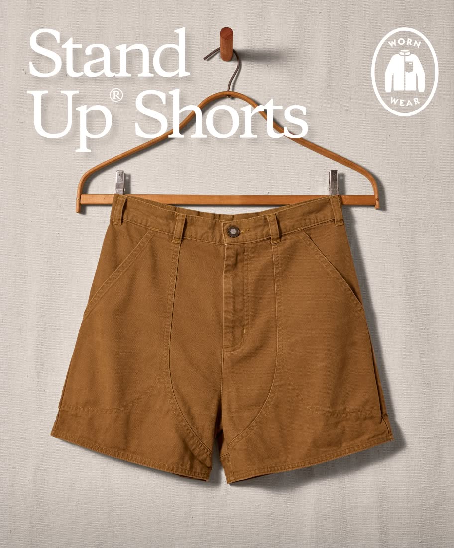 A pair of brown Stand Up Shorts hangs on a clothes hanger.