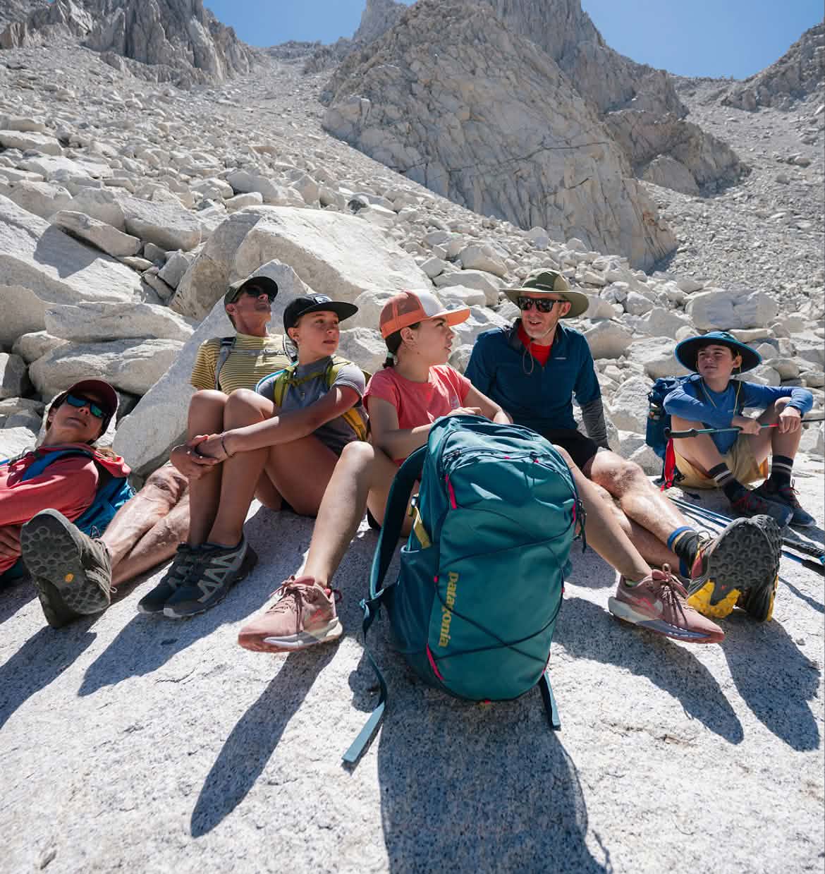 Six people sit on granite above timber line.