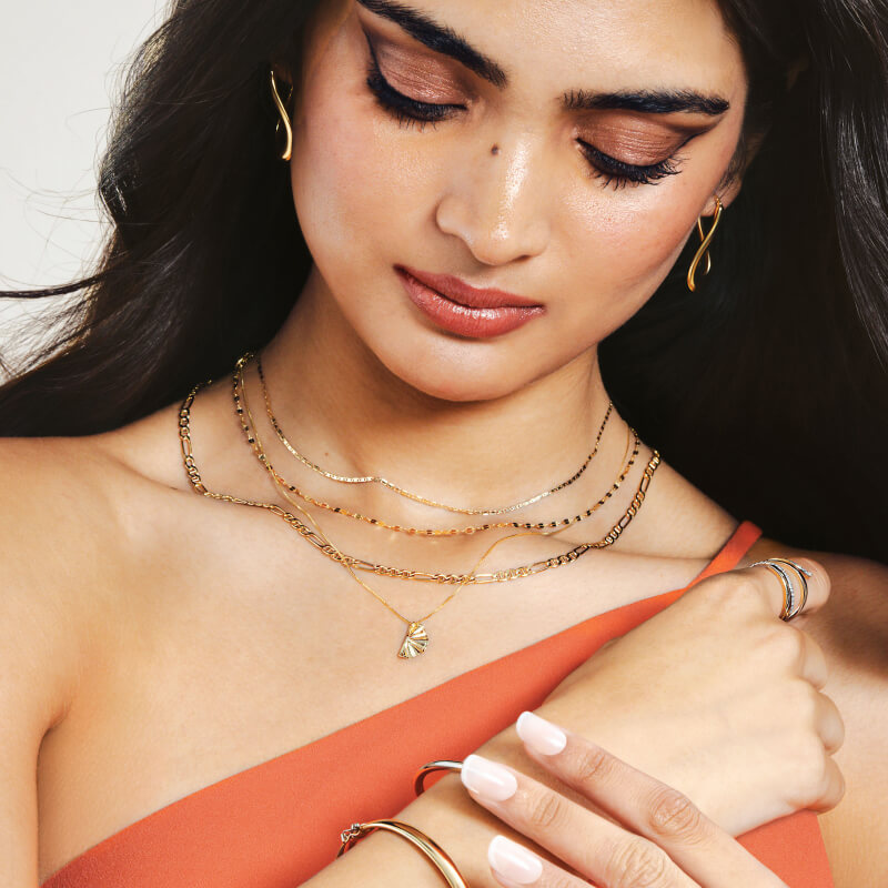 A woman poses, showcasing stunning Gold Bracelets, Earrings and Rings