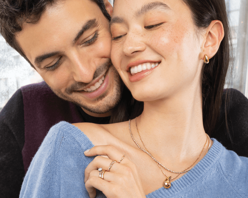 Man embracing woman wearing beautiful rings, necklaces and earrings.