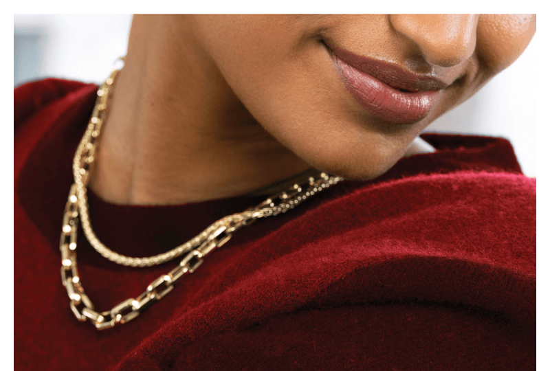 Beautiful woman showcasing layers of elegant chain necklaces.