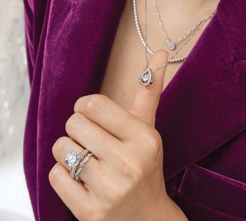 Modal wearing layered necklaces and white gold engagement ring and wedding band. 