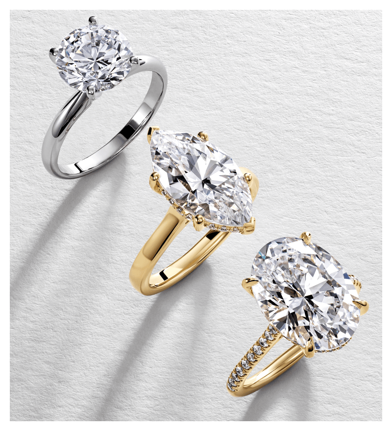 Three different solitaire engagement rings with white and yellow gold bands and round, marquise and oval cut stones. 