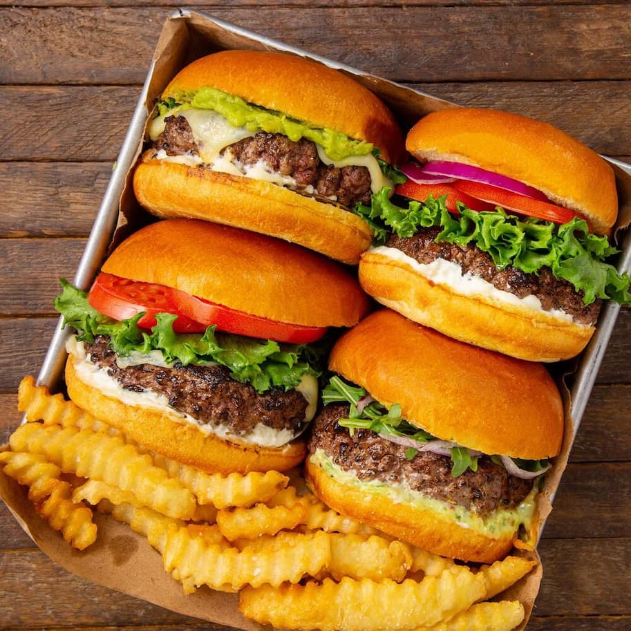 an image of a tray of hamburgers and french fries on a wooden table
