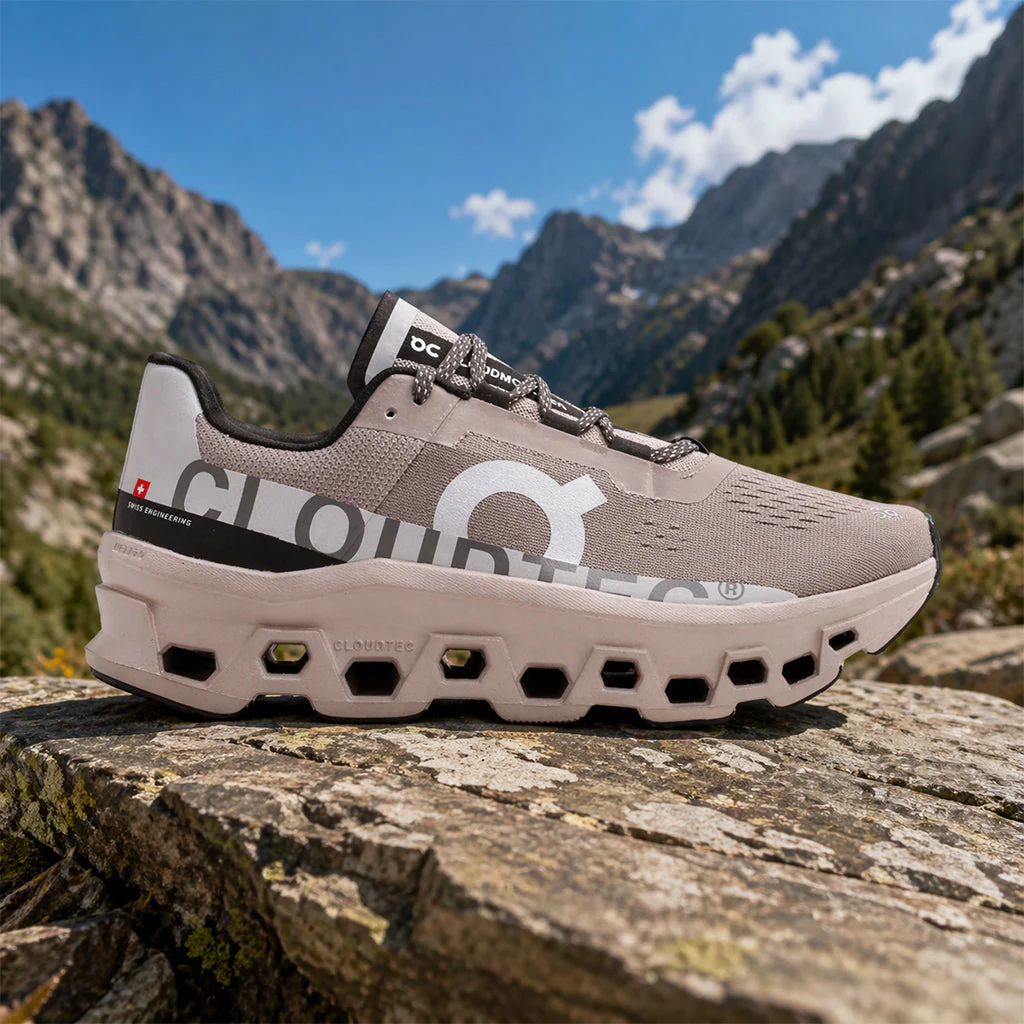 On Cloudtec running shoe displayed on a rocky mountain outcrop with alpine peaks in the background.