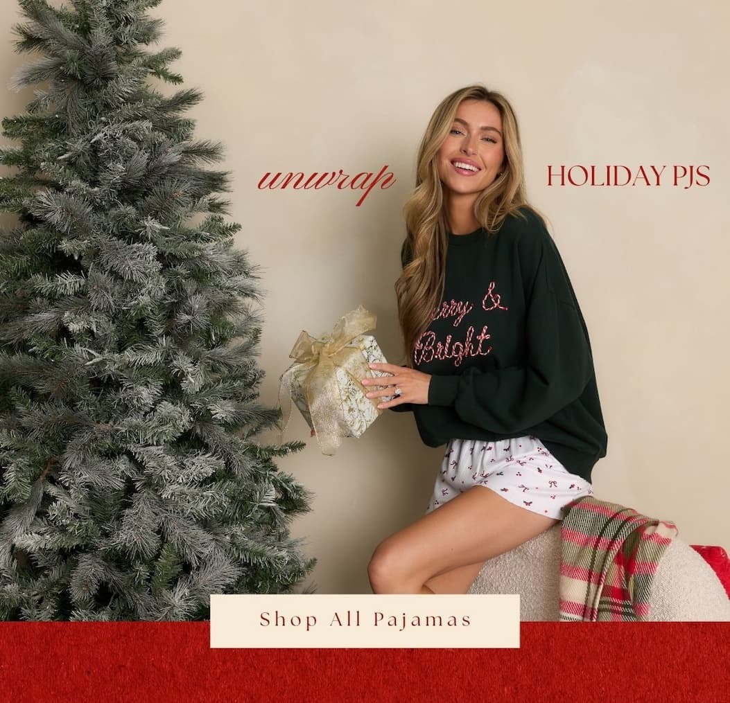 'unwrap holiday pjs.' Image of model wearing a Christmas sweatshirt and holiday pajama bottoms. Button: 'Shop All Pajamas.' 