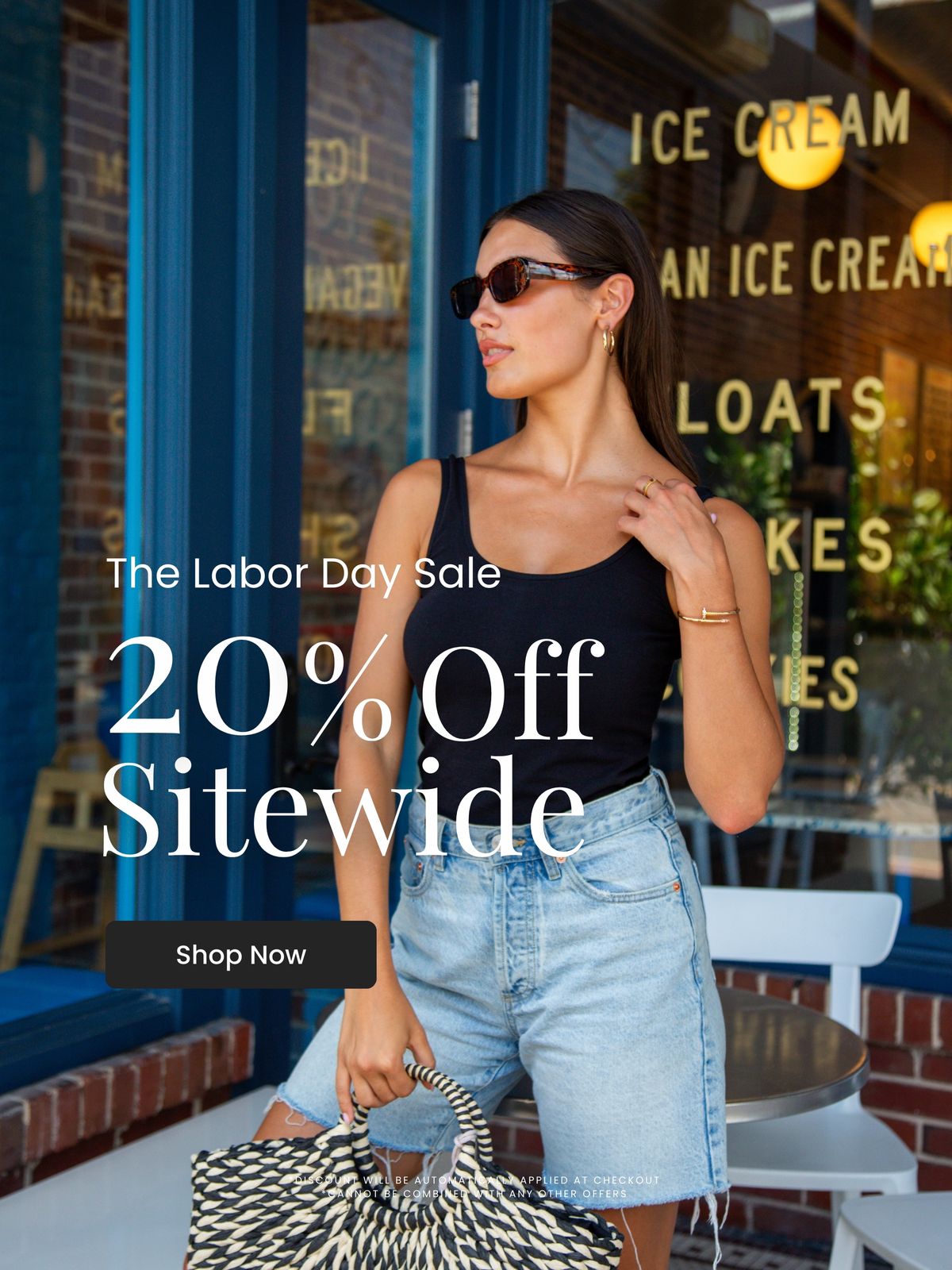 Woman wearing a black tank top and denim shorts holding a woven bag, promoting Rhonda Shear Intimates Labor Day Sale — 20% off sitewide. Shop Now.