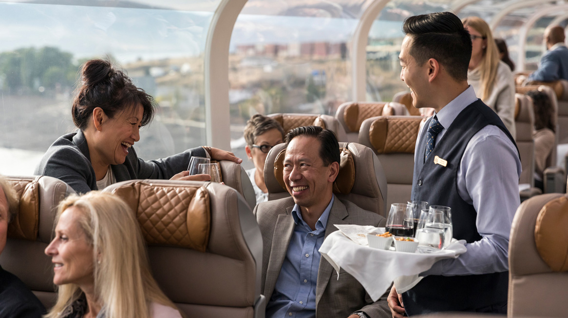 Onboard Host serving wine to couple in GoldLeaf dome.