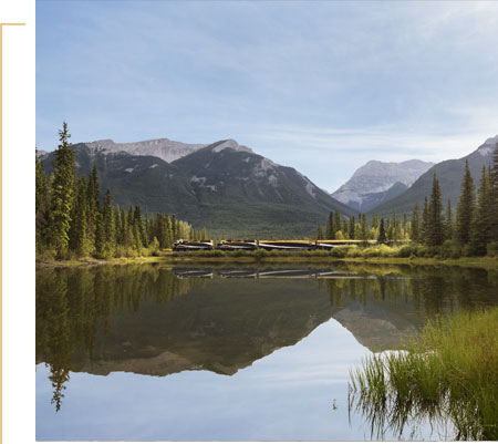 Rocky Mountaineer travelling through lake and mountain scenery.