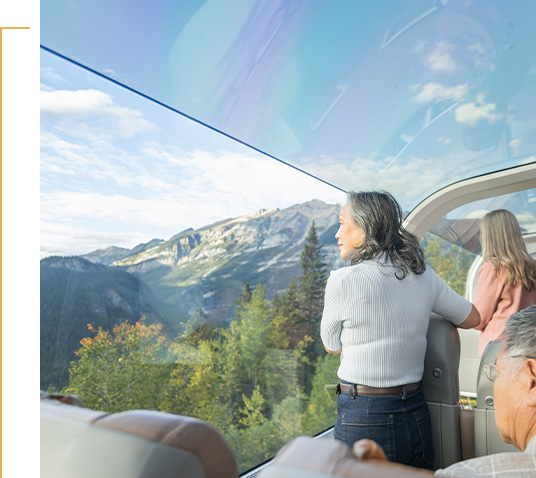 Guest looking at mountain scenery from a Rocky Mountaineer glass-dome coach.