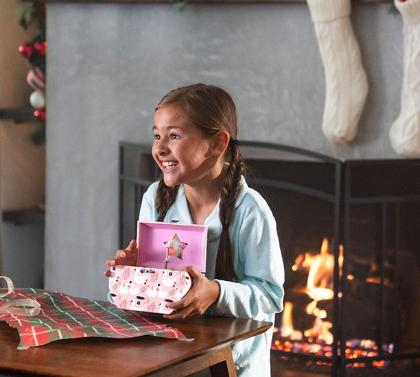 Girl happily holding a ballerina music box from a Ross store.