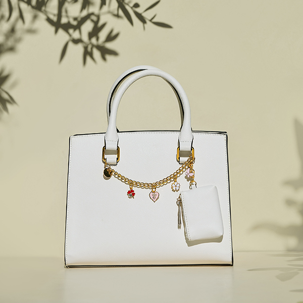 White box bag with gold metal chain and charms across the bag from Ross.