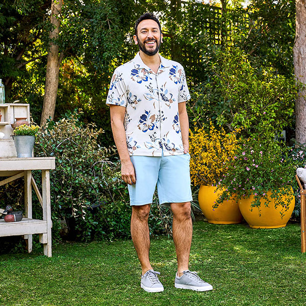 Man wearing short sleeved shirt and shorts in garden. 