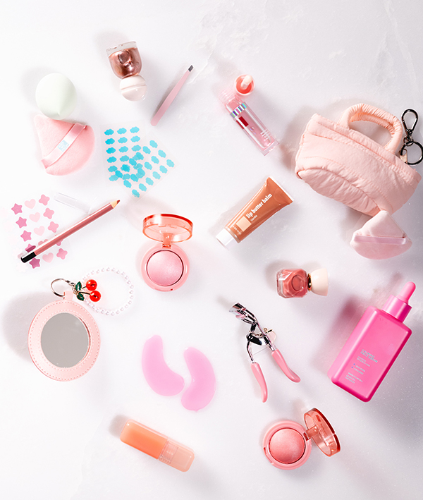 Lip liner, eyeshadow, mini mirror, eye lash curler, lip butter balm and other various beauty products on white table. 