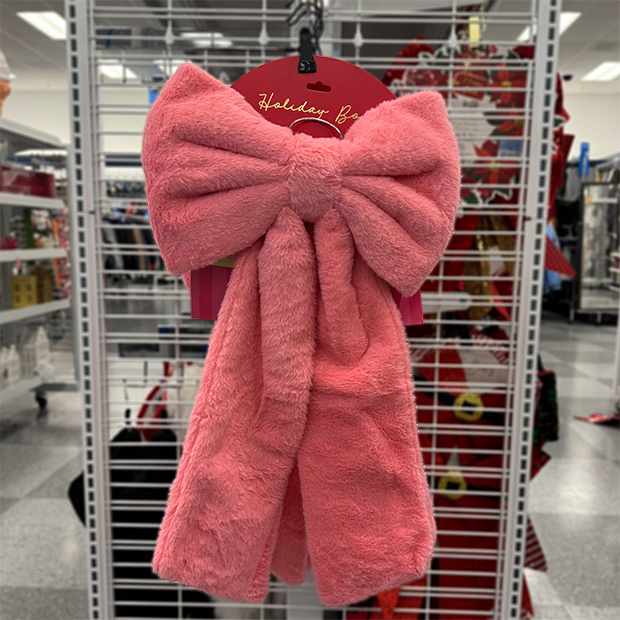 Large pink plush bow with long tails hanging in store at Ross. 
