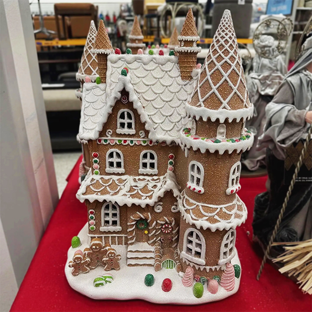 Decorative gingerbread house with white icing details, candy accents, and two tall towers displayed in store at Ross. 