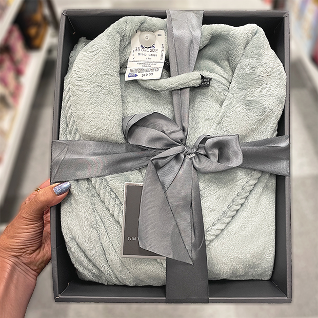 Soft light gray plush robe neatly folded in a gift box with a silver satin ribbon tied in a bow. 