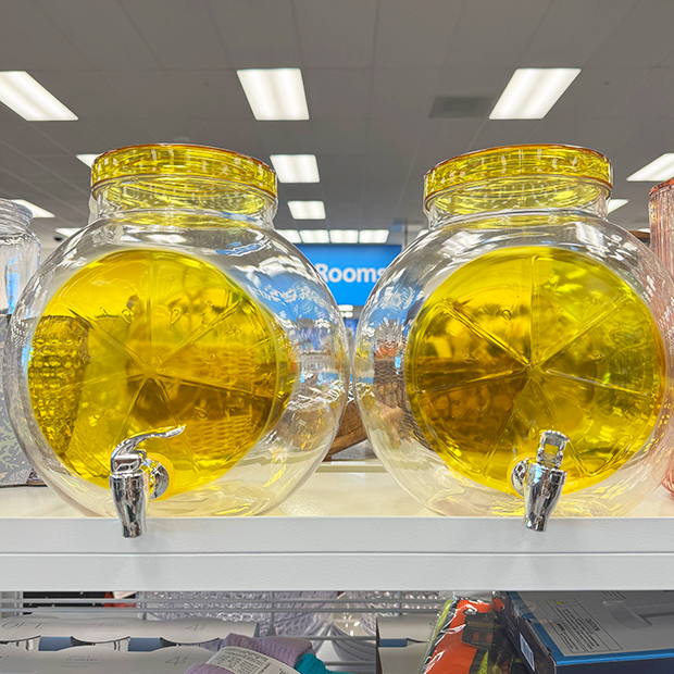 Two round clear lemon shaped beverage dispensers with a spout. 