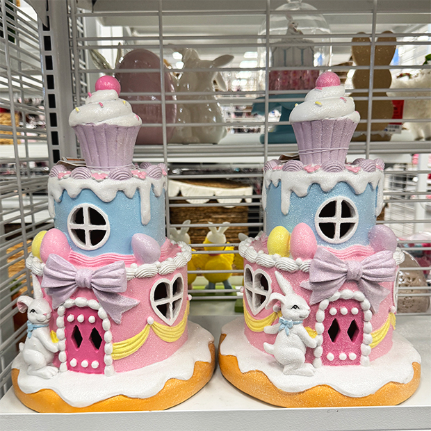Pastel Easter decorations featuring a bunny holding a basket beside an egg-shaped house with spring details.