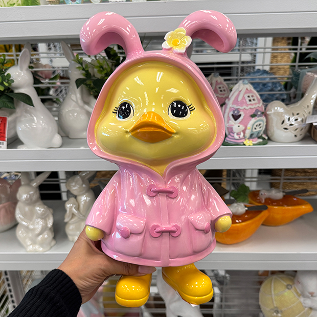 Pink bunny figurine wearing a raincoat with hood and yellow boots 
