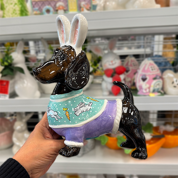 Decorative dog figurine wearing bunny ears and a pastel outfit with Easter-themed patterns. 