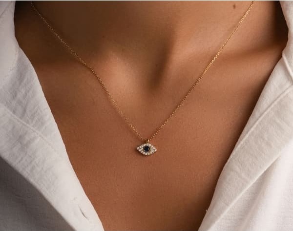 Woman wearing a delicate evil eye necklace in gold