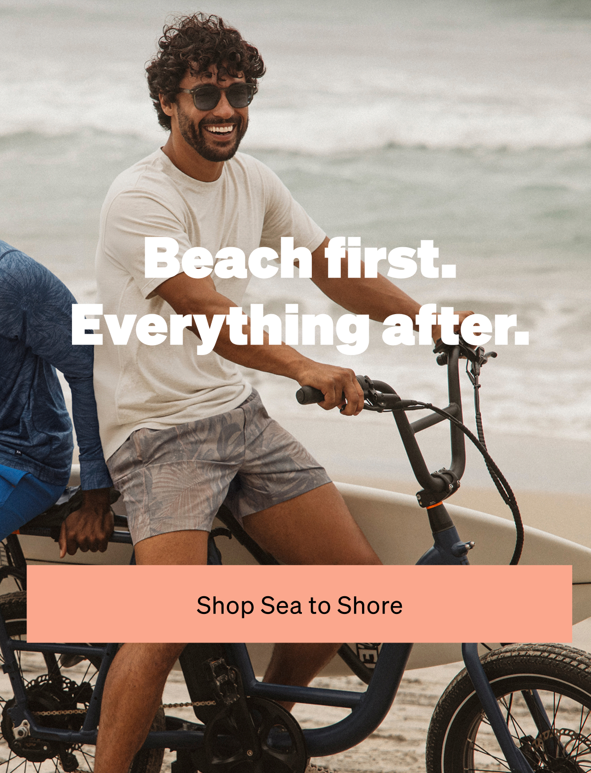 Man riding a bike by the beach wearing swim shorts with “Beach first. Everything after.” text overlay