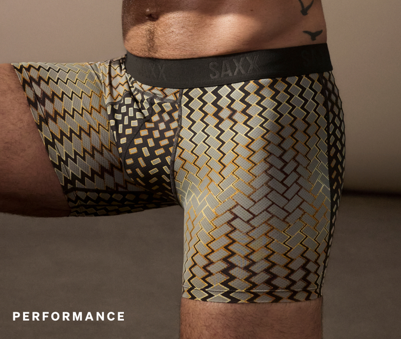 Model wearing patterned SAXX Smooth Flex boxer brief with supportive fit, labeled Performance.