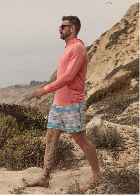Man wearing printed swim shorts and coral cooling tops on the beach