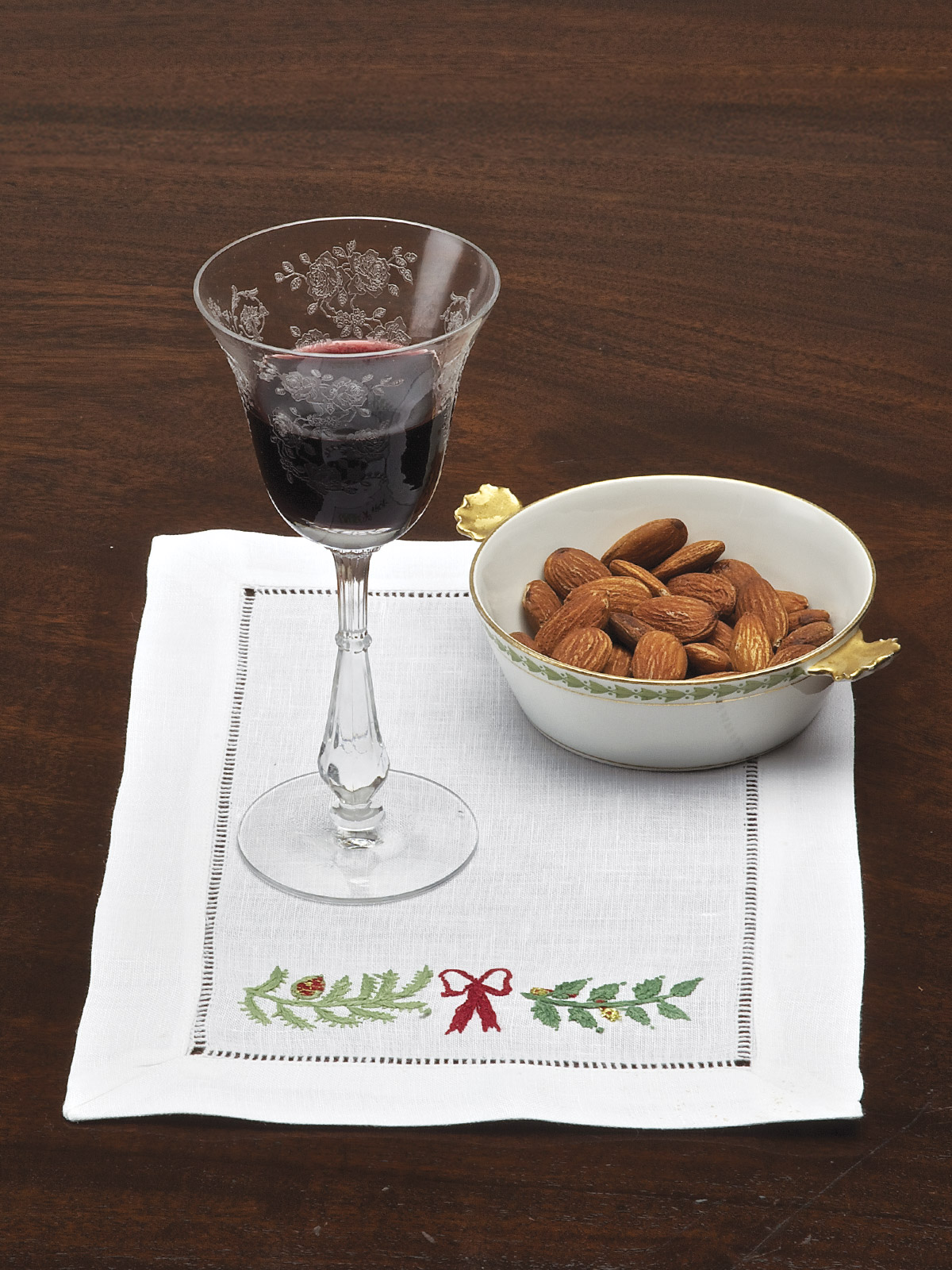 Let the festivities begin. Hand-embroidered Table Collection with boughs of holly and bows in Green and Red