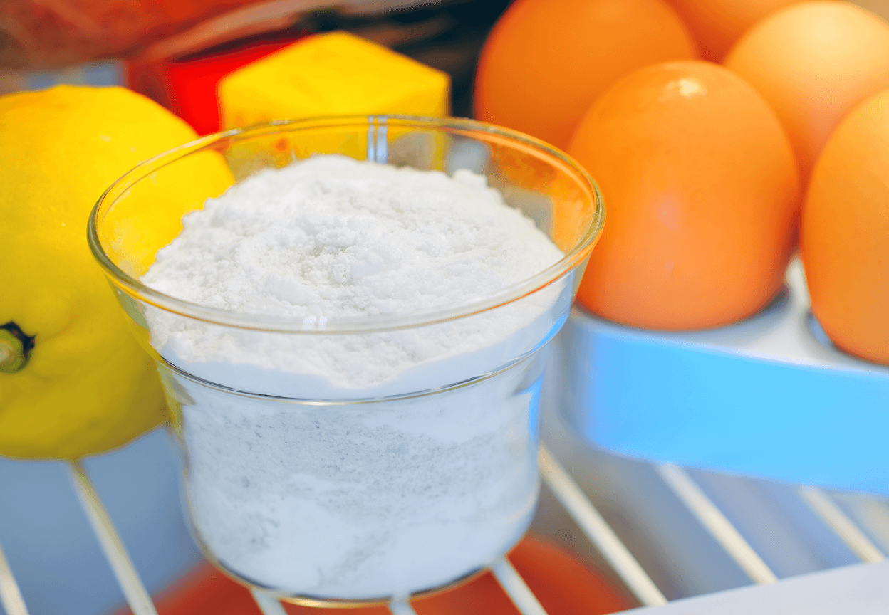 Baking soda in a jar next to fruits in a fridge
