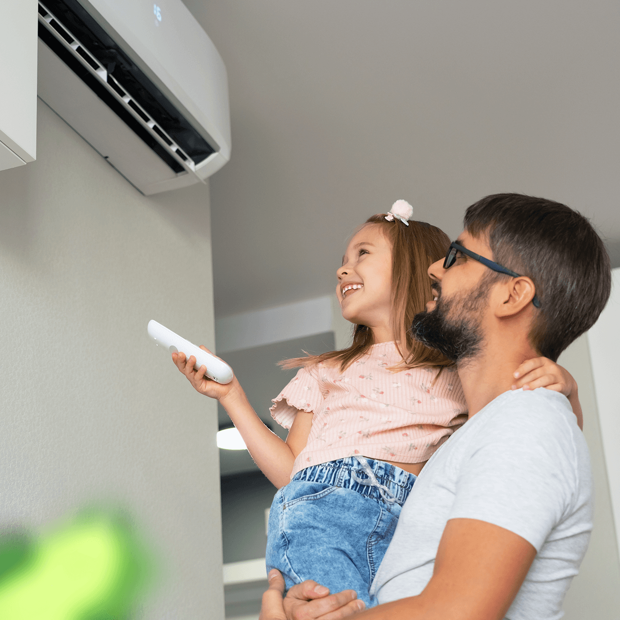 Smiling child being held up by father near an AC unit