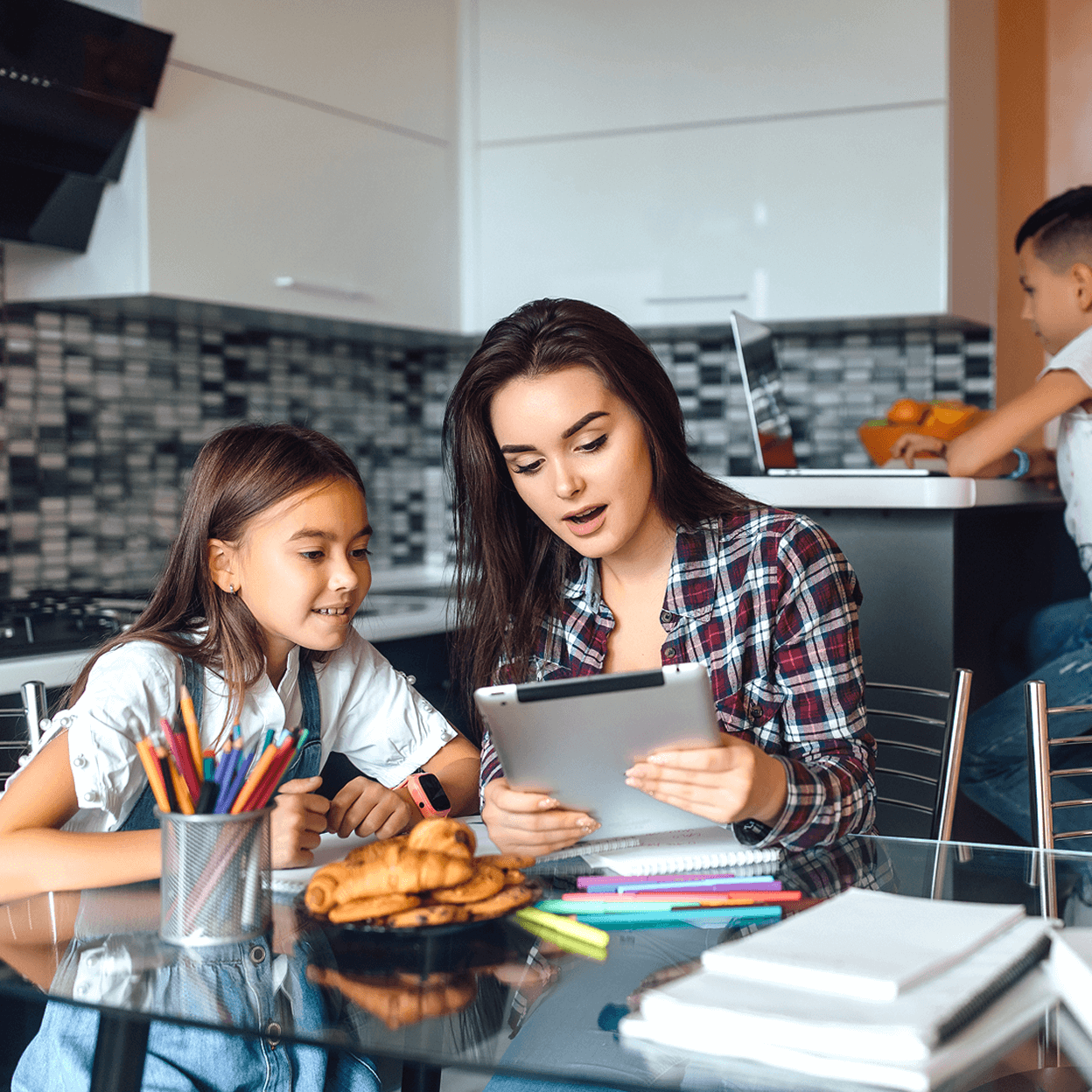 A girl and a woman sitting at a kitchen table while they look at an iPad