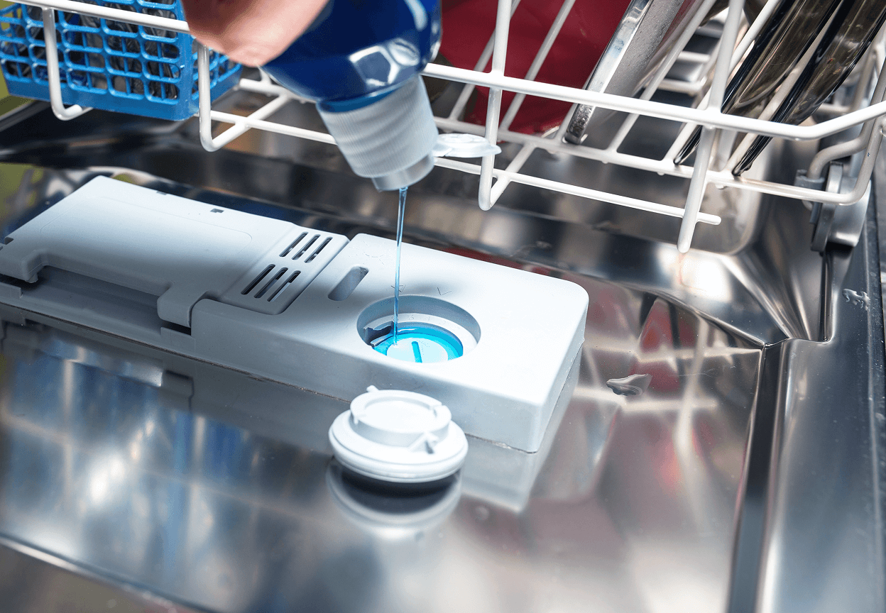 A person pouring in dishwashing liquid into a dispenser