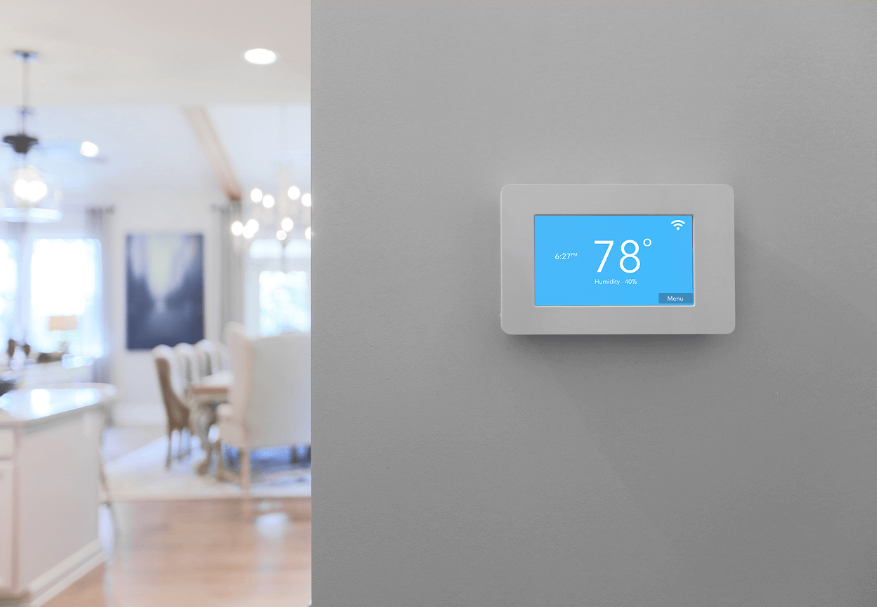 A thermostat on the wall with a blurred background of a kitchen