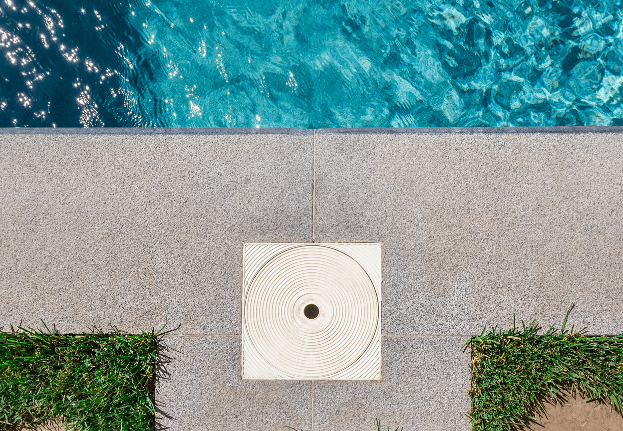 A top pool filter opening surrounded by concrete