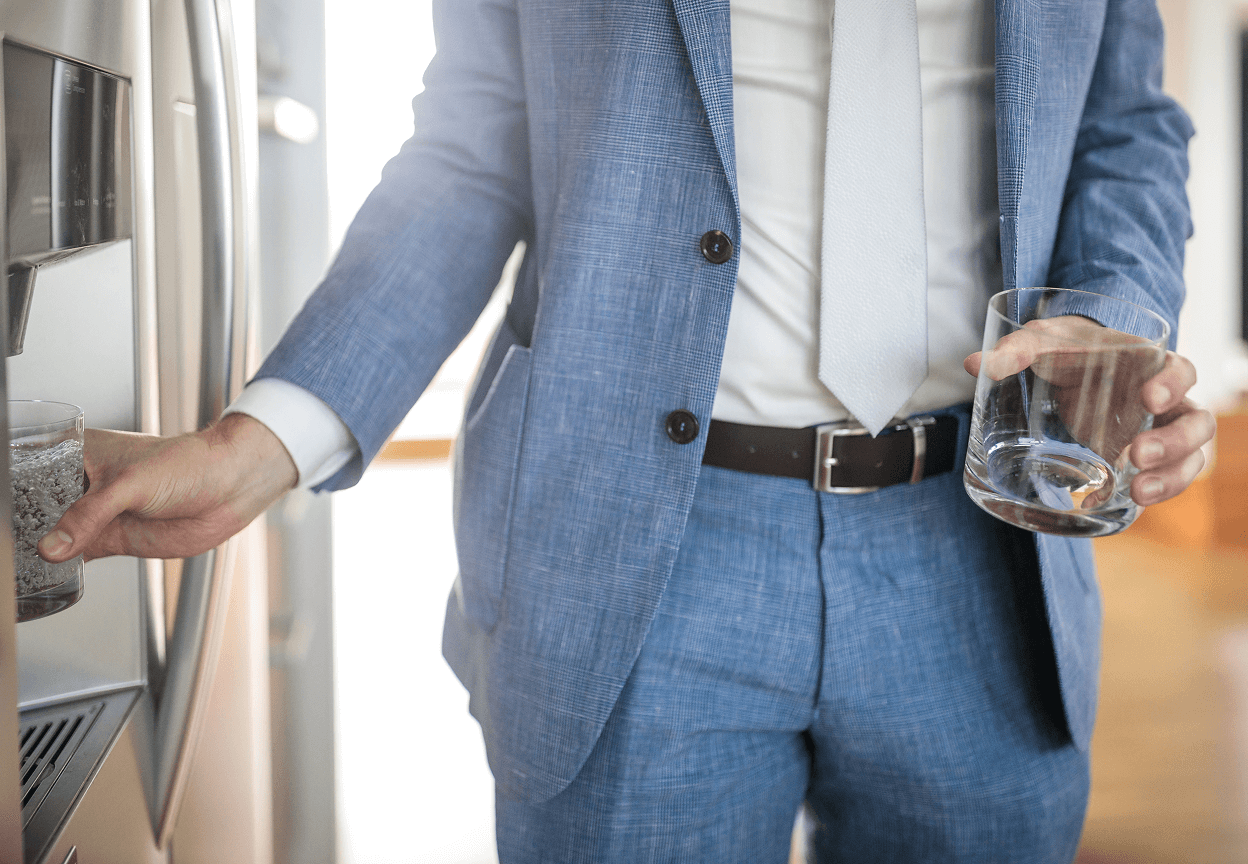 A man getting water from a fridge water dispenser