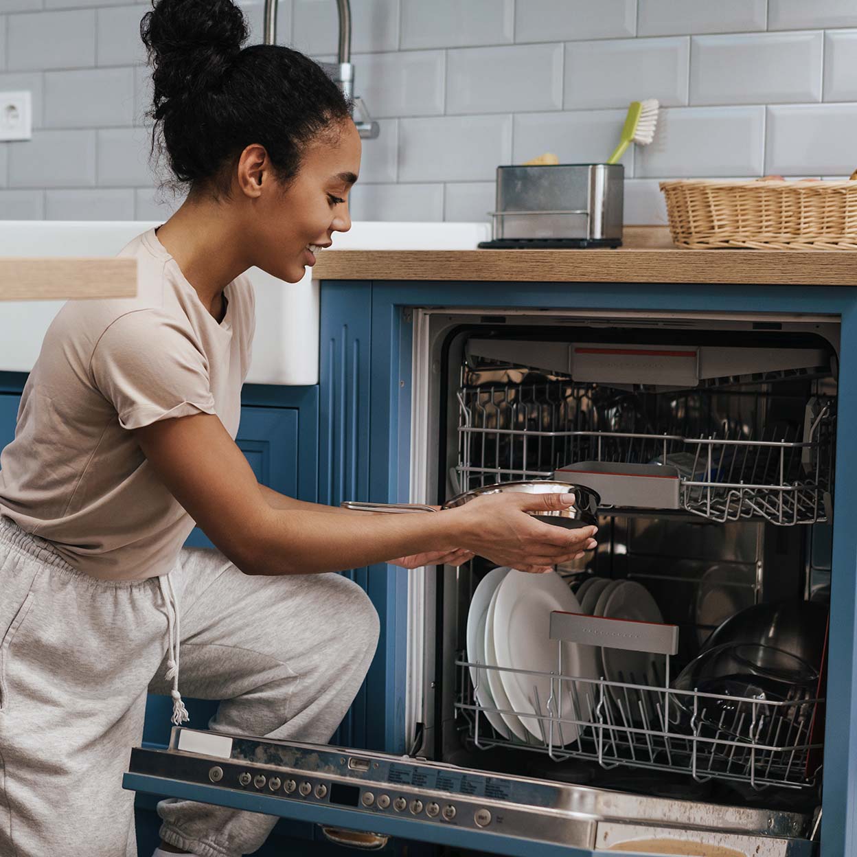 A woman putting away clean dishes from the dishwasher