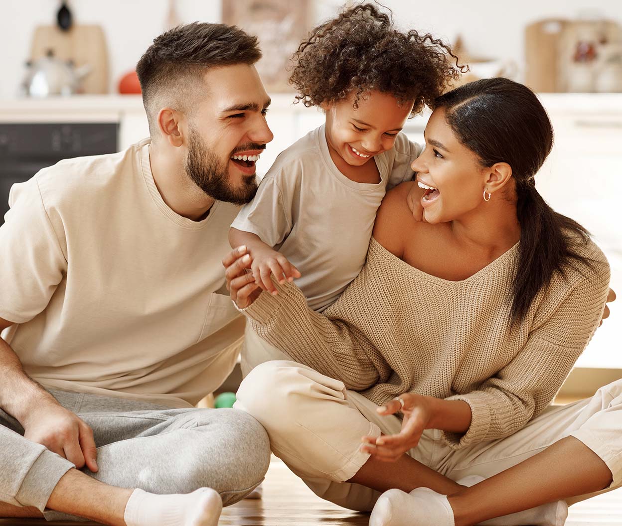 A couple laughs with their child while sitting together at home
