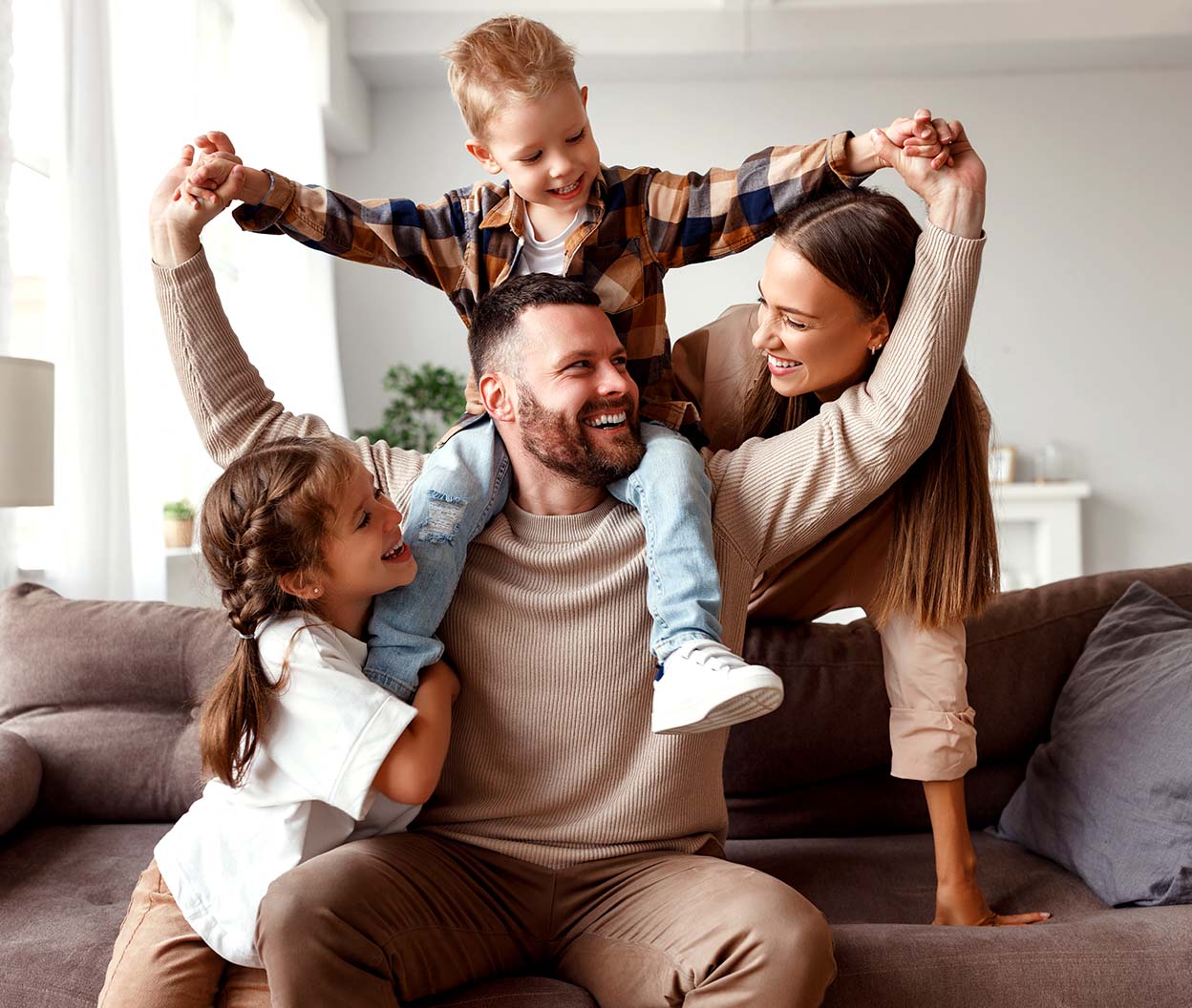 A smiling family relaxes on a couch while the kids play, enjoying a comfortable living room