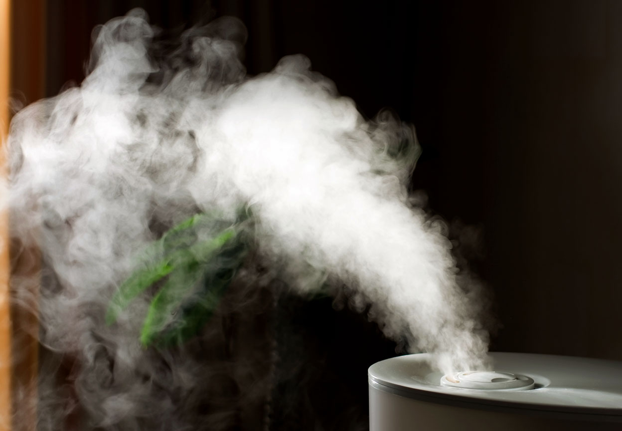 A tabletop humidifier releases a steady stream of mist into the air