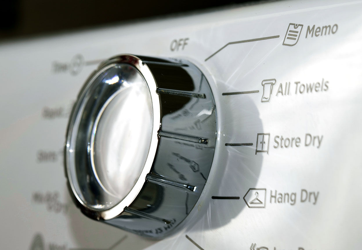 Close-up of a dryer cycle knob with settings like Store Dry and Hang Dry