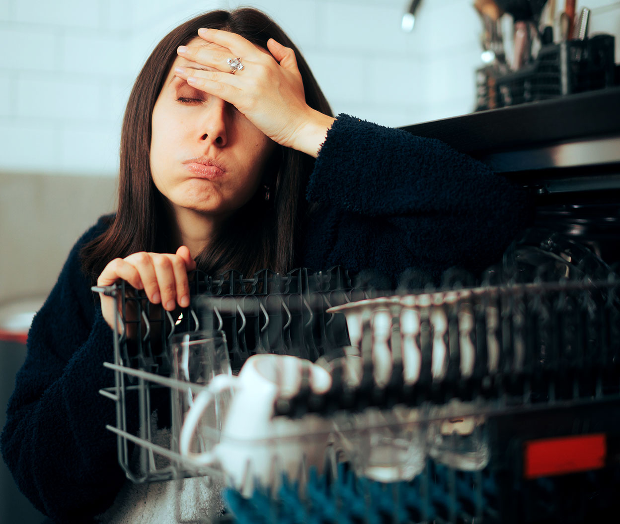 A homeowner looks at their appliances while wondering why everyday performance like cleaning, cooling, and drying starts to slip
