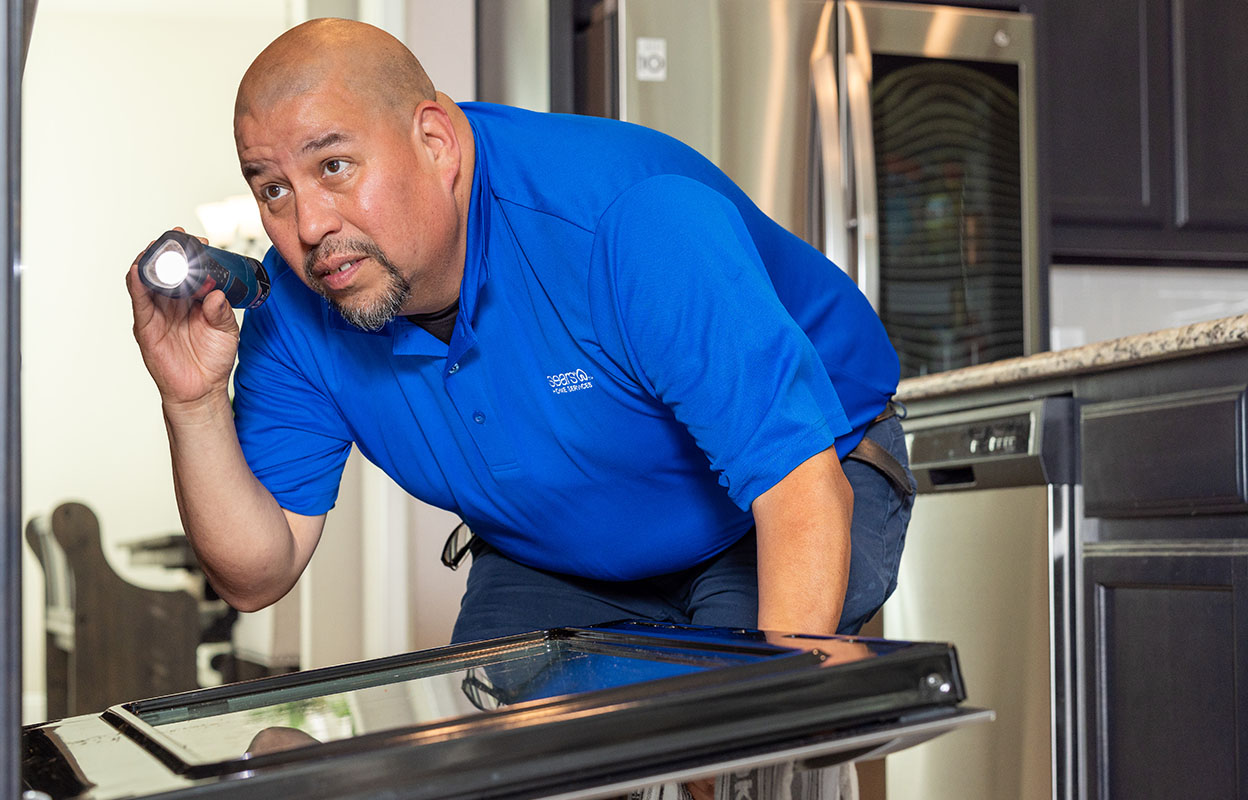 A Sears Home Services techinician looks in an oven