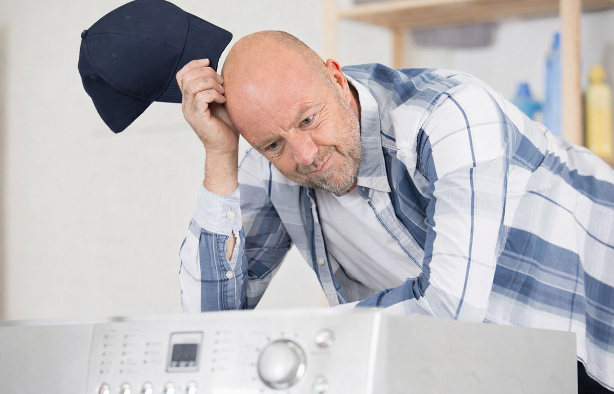 A man scratches his head as he looks over the dryer