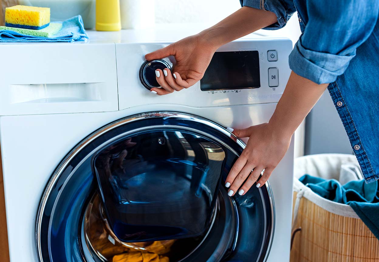 Close-up of a person adjusting the controls on a front-load washing machine
