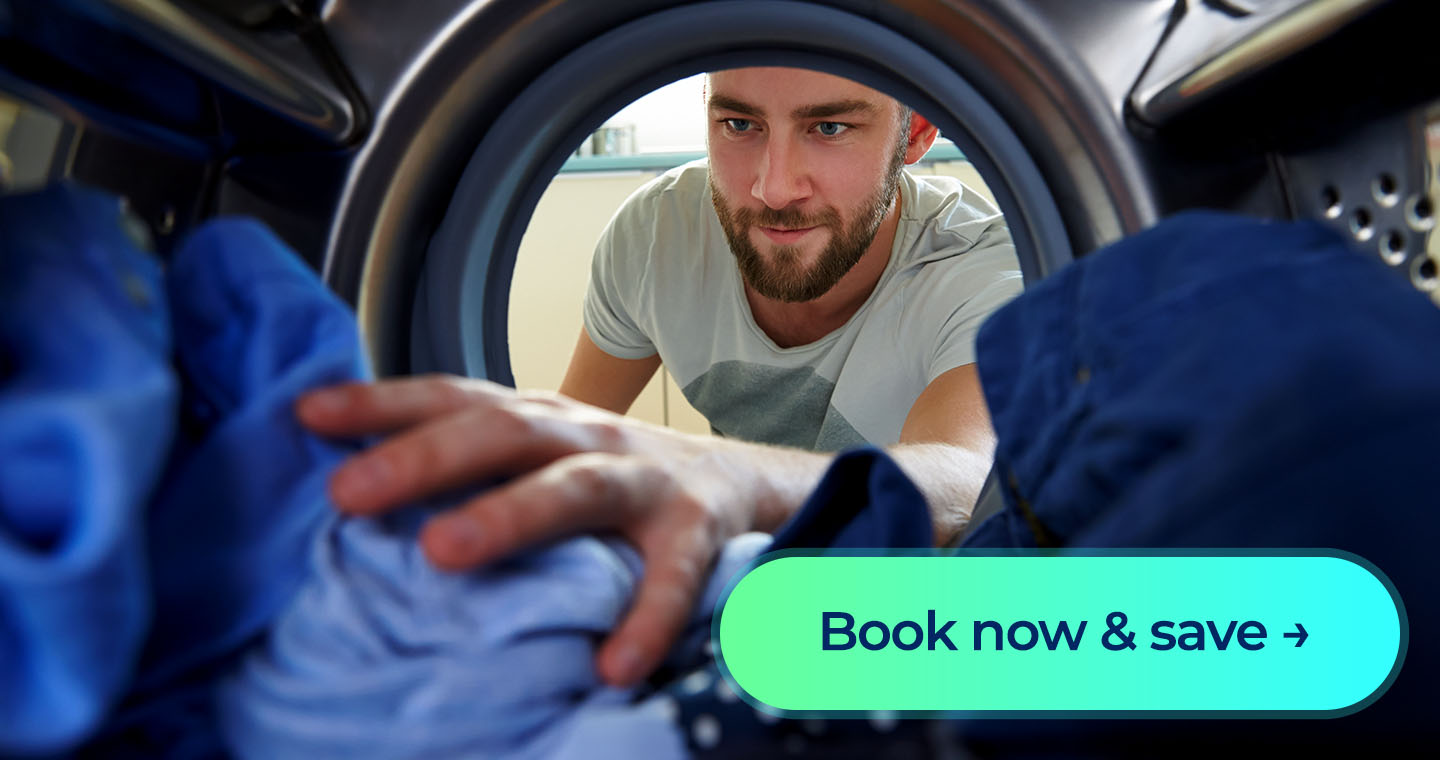 A man smiles as he reaches into his dryer for his clothes